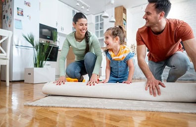 Mom and dad roll out carpet with child