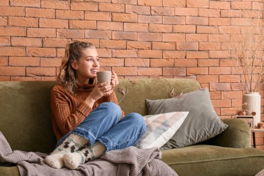 Woman sitting on couch in home with cup of coffee