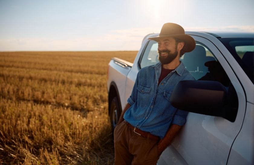 A man and his new truck in a field of alfalfa
