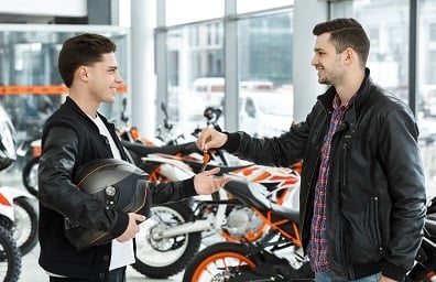 Salesman hands keys to young male motorcycle customer