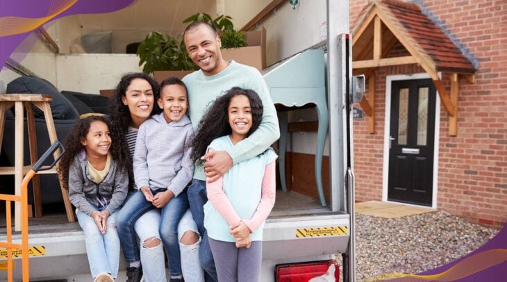Happy family standing outside their new home in front of moving truck.