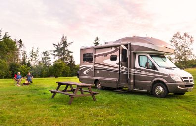 Una pareja está sentada junto a su autocaravana, disfrutando de una agradable fogata.