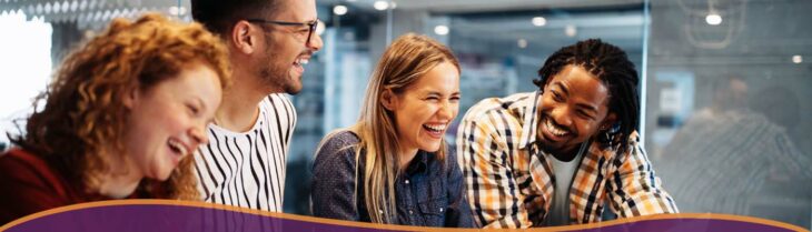 Group of four friends laughing together at work.
