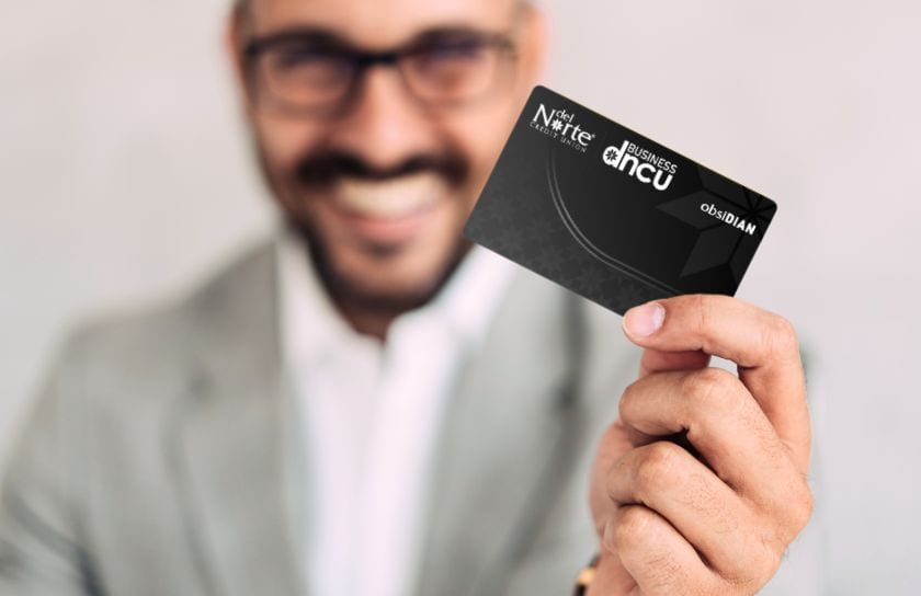 A man holds a Del Norte Credit Union Business credit card.