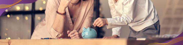 Mom and son putting coins into a blue piggy bank.