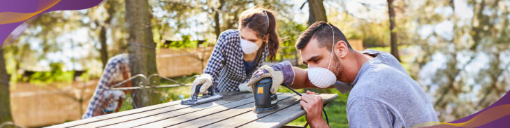 Couple working on sanding a door in backyard.