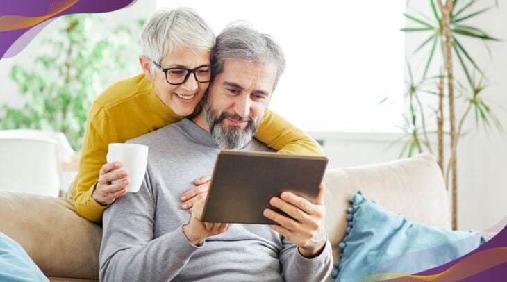 Senior couple man and woman looking at tablet device together and smiling.