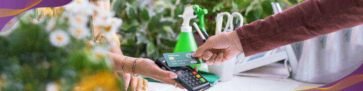 Customer using contactless credit card payment at shop.