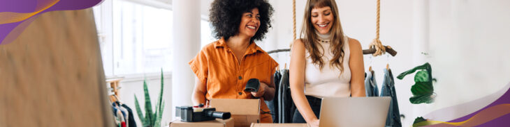 Happy business women working on laptop and shipping orders in boxes.