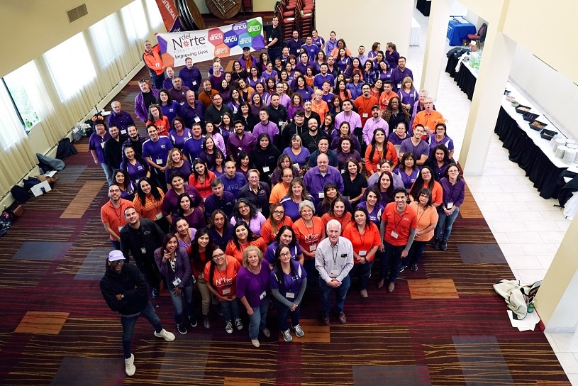A photo looking down on a lobby full of smiling DNCU employees