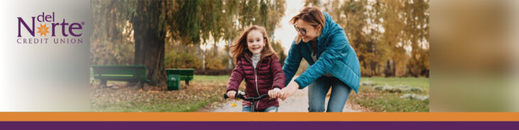 Mom helping daughter learn how to ride a bike outside in park