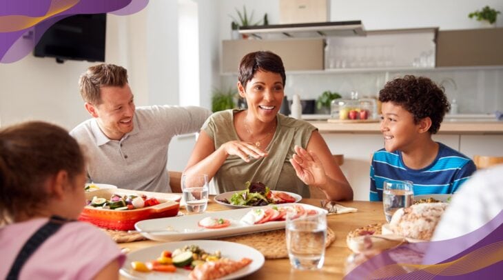 Happy family eating a meal together at home at kitchen table.