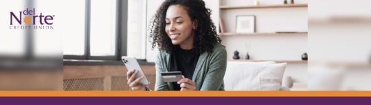 Smiling woman looking at smartphone and holding credit card