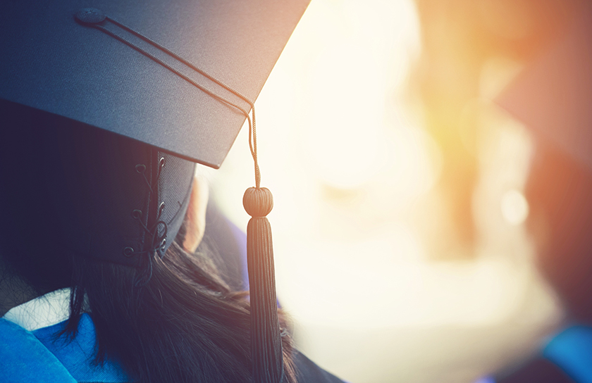 Back of woman's head with cap and gown at graduation ceremony