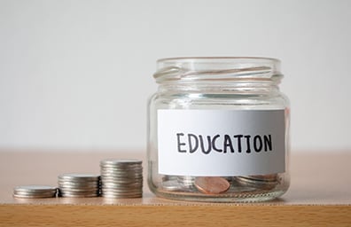 A glass jar of coins with the word education on label