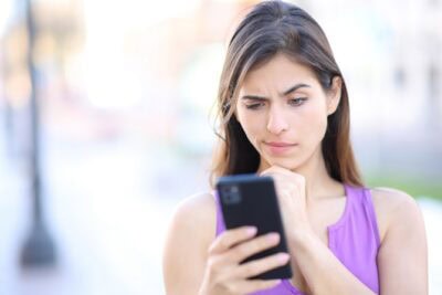 Suspicious woman checks phone in the street