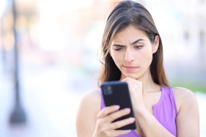 Suspicious woman checks phone in the street