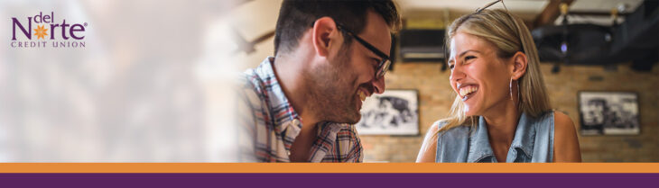 Man and woman on date at restaurant smiling at each other.