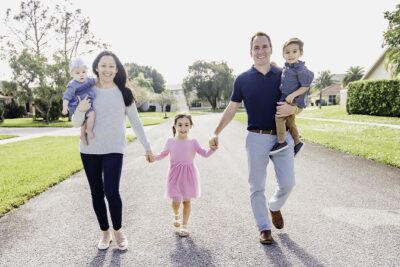 A man and a woman hold their kids' hands.