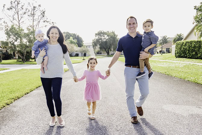 A man and a woman hold their kids' hands.