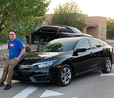 Young man sits on hood of new vehicle