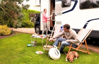 A couple barbeques in front of their new RV.