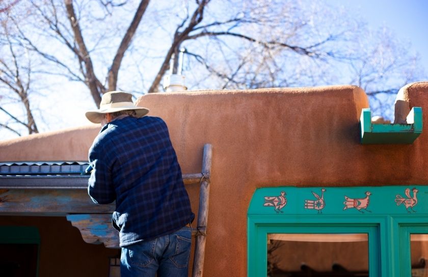 Person cleaning their gutters on a New Mexican home