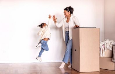 Una niña pequeña choca las palmas con su madre mientras empacan para mudarse a su nueva casa.