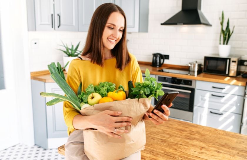 A woman looks at her phone after grocery shopping.