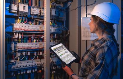 A woman studies the wiring and breakers.