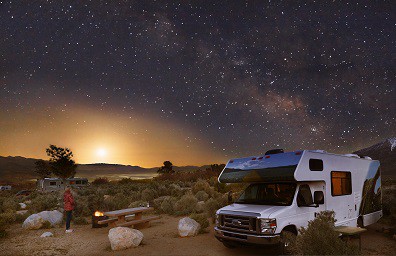 RV parked at campsite under star filled night sky