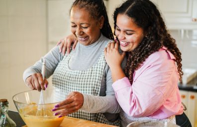 A young girl and her mother bake a cake.