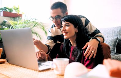 A couple checks their laptop and they are happy.
