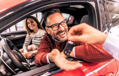 An excited man gets the keys to his new car.