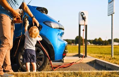 A man and his son charge their electric car.