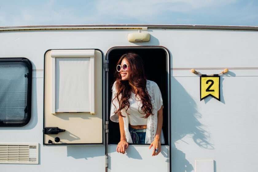 Young woman smiles as she looks outside from within her RV