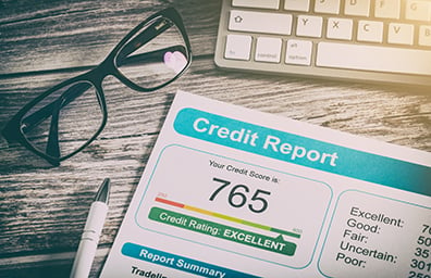 Laptop, eyeglasses and credit report document on top of table