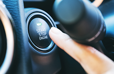 finger pushing the start button on new car