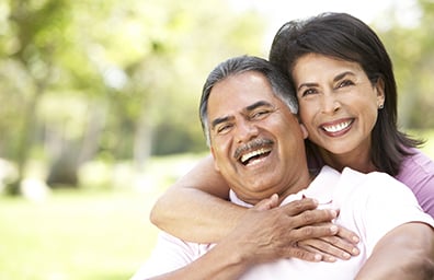 Hispanic couple hugging and smiling outdoors in park