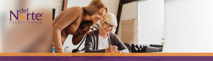 Older mother and daughter sitting at table together looking over papers