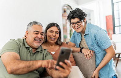 A young person looks at adults' phone with a smile