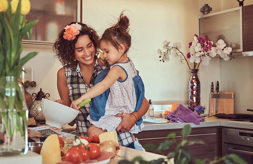 A young girl helps her mother prepare a meal in the kitchen