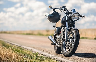 Motorcycle with helmet hanging from handlebar on empty desert road