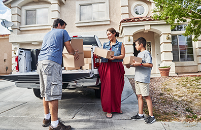 Man woman and young boy unload pick up truck in driveway of new home