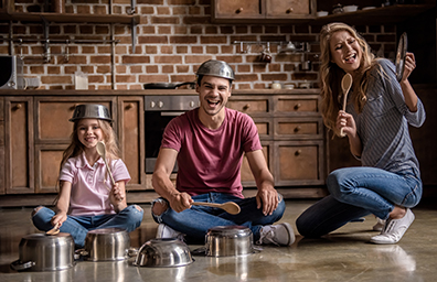 Funny family playing band with dishes on kitchen floor and bowls on heads