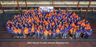 All DNCU employees stand together in lobby with banner of available services